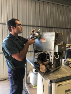 An AA King technician replacing a fan in a fridge motor