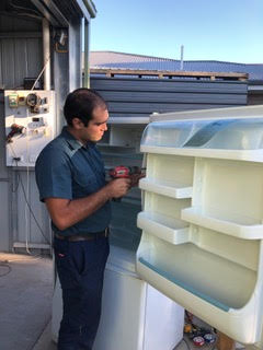 An AA King fridge mechanic repairing a fridge door